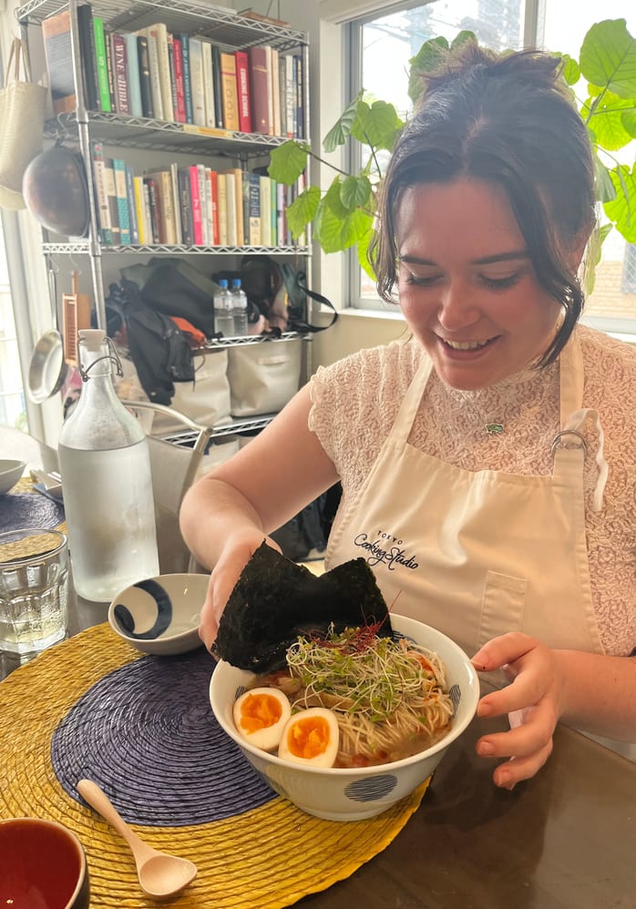 A guest topping a bowl of ramen she made